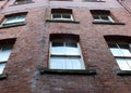 Upwards view of a large old red brick building with rows of narrow windows Royalty Free Stock Photo