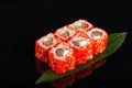 Uramaki philadelphia roll filled with salmon, cucumber, avocado and cream cheese. Philly rolls covered with red flying fish roe Royalty Free Stock Photo