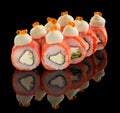 Uramaki Sushi roll with salmon, cheese, cucumber, sauce and caviar on top isolated on black background with reflection