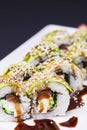 Uramaki sushi roll with smoked eel and unagi on white plate over black background. Japanese cuisine concept Royalty Free Stock Photo