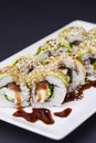 Uramaki sushi roll with smoked eel and unagi on white plate over black background. Japanese cuisine concept Royalty Free Stock Photo