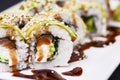 Uramaki sushi roll with smoked eel and unagi on white plate over black background. Japanese cuisine concept Royalty Free Stock Photo