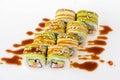 Uramaki tori sushi, a set of green rolls with sesame seeds and unagi sauce isolated on white. Eight pieces of sushi.