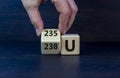 Uranium enrichment symbol. Hand turns the cube and changes the word `238 U` to `235 U`. Beautiful dark background, copy space.