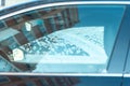 Urban abstract photo through the side windows of the car, the reflection of tall houses in the glass, snow on the window