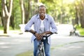 Urban adventure concept. Happy African American guy on fun bicycle ride at city park
