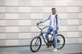 Urban adventure. Happy black man with backpack and bike standing near brick wall outdoors and looking aside, copy space