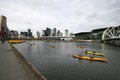 Kayak paddlers on Yarra River, South Wharf, Melbourne, Victoria, Australia. Promenade with coastal cityscape of skyscrapers