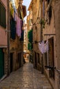 Urban alleyway with brick walls and sun-drenched laundry hung up to dry in Rovinj, Croatia Royalty Free Stock Photo