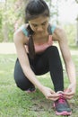 Urban athlete woman tying running shoe laces. Female sport fitness runner getting ready for jogging outdoors on forest path in ci Royalty Free Stock Photo