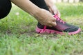 Urban athlete woman tying running shoe laces. Female sport fitness runner getting ready for jogging outdoors on forest path in ci Royalty Free Stock Photo