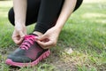 Urban athlete woman tying running shoe laces. Female sport fitness runner getting ready for jogging outdoors on forest path in ci Royalty Free Stock Photo