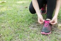 Urban athlete woman tying running shoe laces. Female sport fitness runner getting ready for jogging outdoors on forest path in ci Royalty Free Stock Photo