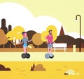 Urban autumn park outdoors activities man woman riding gyroscooter walking city buildings street lamps cityscape concept Royalty Free Stock Photo