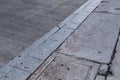 Urban background of finely grooved concrete road and grey stone curb, cracked sidewalk