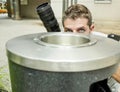 Lifestyle funny portrait of young paparazzi photographer man in action hidden behind city paper basket stalking for shooting excl Royalty Free Stock Photo