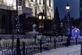 Urban background night christmas landscape, city clock and lights with garlands on the square Royalty Free Stock Photo