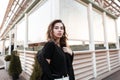 Urban beautiful young woman in a black coat in a fashionable t-shirt in white jeans with a pose posing Royalty Free Stock Photo