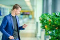 Urban businessman talking on smart phone inside in airport. Casual young boy wearing suit jacket. Caucasian man with Royalty Free Stock Photo