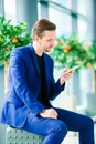 Urban businessman talking on smart phone inside in airport. Casual young boy wearing suit jacket. Caucasian man with Royalty Free Stock Photo