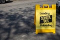 Urban city road and the street no parking loading schools buses only yellow and black sandwich board street sign Royalty Free Stock Photo