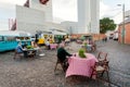 Urban cityscape with people relaxing at outdoor restaurant with fast food trailers on street