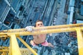 Urban climbing: rock climber hanging on jib of construction crane with one hand