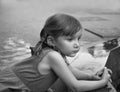 An urban close up serious portrait of a little girl near the granitic parapet wall of a fountain