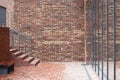 Urban day shot of a red brick terrace with benches and stairs in front of a glass full height open plan floor to ceiling windows