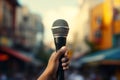 Urban discourse Hand holds microphone, poised for city storytelling Royalty Free Stock Photo