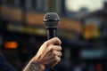 Urban discourse Hand holds microphone, poised for city storytelling Royalty Free Stock Photo