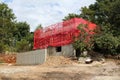 Urban family house under construction with metal building scaffolding on top wrapped with red protective mesh surrounded with Royalty Free Stock Photo