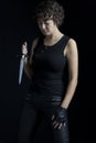 An urban fantasy woman wearing all black and holding a dagger