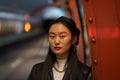 Urban fashion portrait of chinese woman wear leather beret and jacket, earrings at subway platform Royalty Free Stock Photo