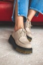 Urban fashion shoes. Casual sneakers on teen girl legs in denim jeans. Teenage sitting on red old leather chair Royalty Free Stock Photo