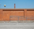 Urban industrial background. A brick wall with an old factory chimney in front of a concrete road Royalty Free Stock Photo