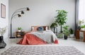 Urban jungle in bedroom with double bed, lamp and carpet