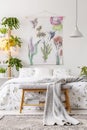 Urban jungle bedroom interior with a bed dressed in white and green bedding and painted art on the wall Royalty Free Stock Photo