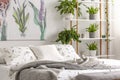 Urban jungle bedroom interior with plants in pots beside a bed dressed in organic cotton linen of white color with green print. Re Royalty Free Stock Photo