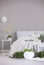 Urban jungle and white balloons in elegant bedroom interior with king size bed and copy space on the empty grey wall Royalty Free Stock Photo