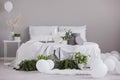 Urban jungle and white balloons in fashionable bedroom interior with large bed with cozy bedding, real photo with copy space on Royalty Free Stock Photo