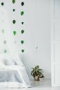 Urban jungle in white bedroom interior with green leafs on empty wall Royalty Free Stock Photo