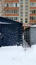Urban landscape with dark blue grunge ribbed wall in snowdrift on foreground. Cityscape in winter. Retro style garage exterior.