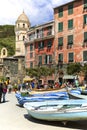 Urban landscape, port town, colorful boats and walking tourists, Vernazza, Cinque Terre, Italy