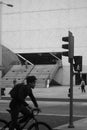 Urban lifestyle in monochrome - Modern building and a cyclist passing by in a blur, a traffic light and city road -