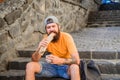 Urban lifestyle nutrition. Carefree hipster eat junk food while sit on stairs. Hungry man snack. Junk food. Guy eating Royalty Free Stock Photo