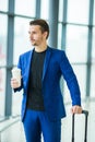 Urban man with coffee inside in airport. Casual young boy wearing suit jacket. Caucasian man with cellphone at the Royalty Free Stock Photo