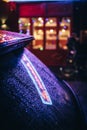 Urban night scene with colourful bright neon lights shining and reflecting on a windshield glass car covered by raindrops on a wet Royalty Free Stock Photo