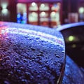 Urban night scene with colourful bright neon lights shining and reflecting on a windshield glass car covered by raindrops on a wet Royalty Free Stock Photo