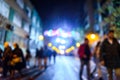 Urban night scene with people walking out of focus with colored background